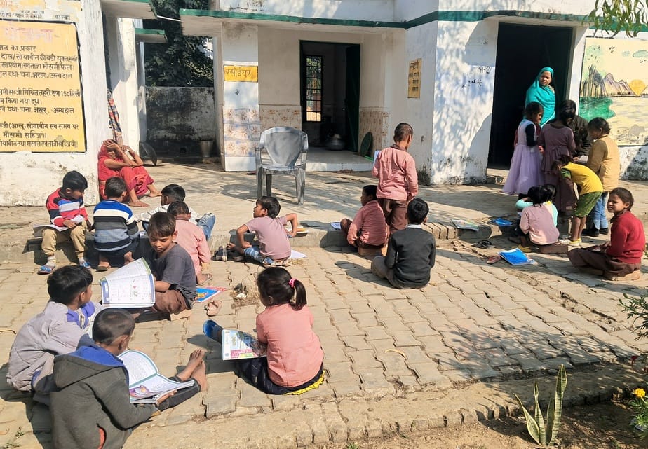 Children sitting on the ground and taking exams, without even a sweater on their body