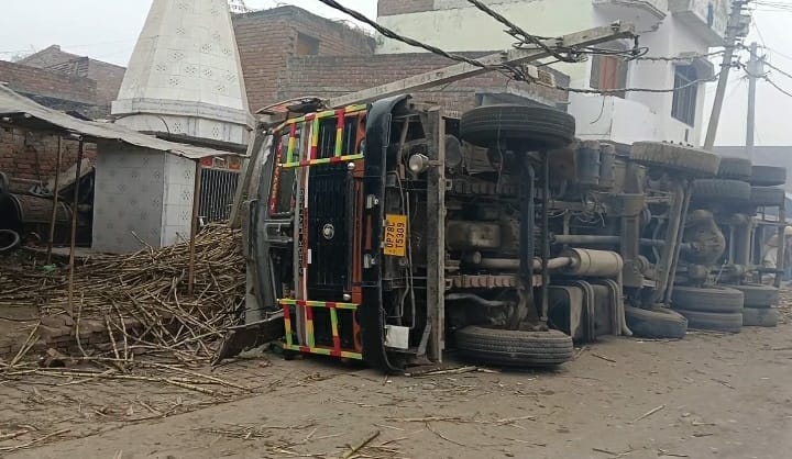 An overloaded truck overturned in Dhai village; people narrowly escaped injury.