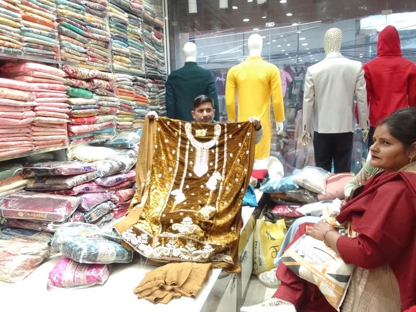 कपड़ों की दुकान में मखमल के सूट की खरीददारी करती हुई महिला। 