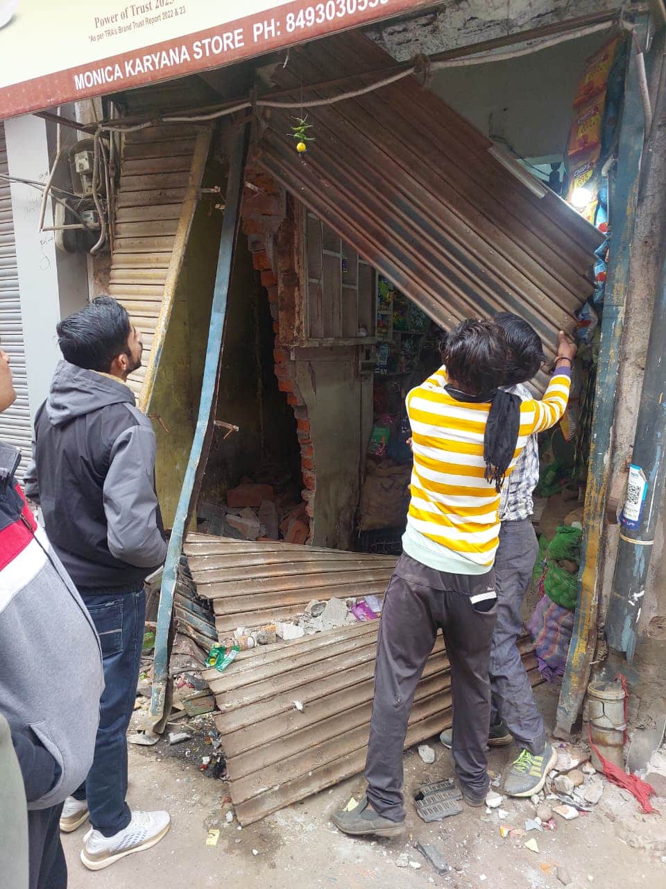 कार की टक्कर से दुकान का टूटा शटर।