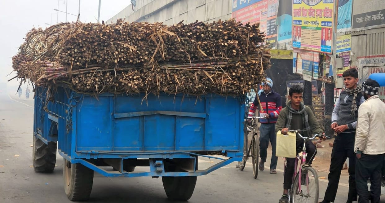 Overloaded vehicles carrying sugarcane are speeding on the highway in dense fog without reflectors.