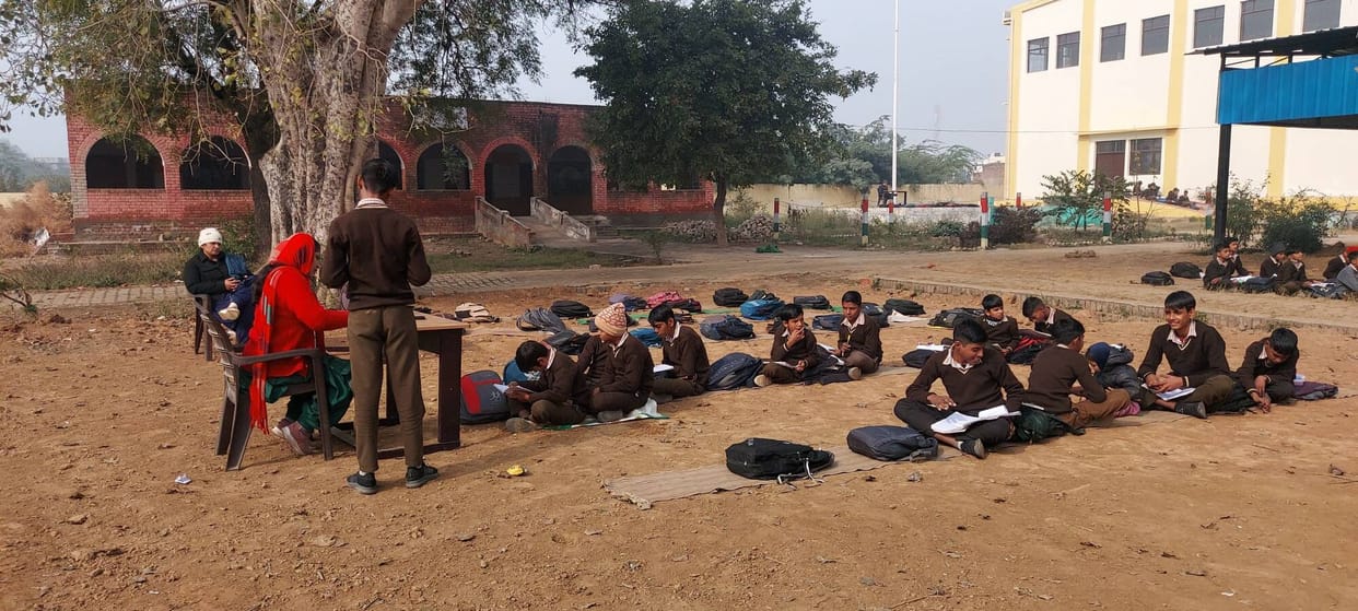 Children forced to read on the ground under the cold sky