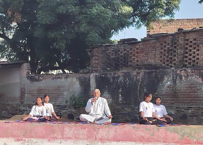 स्कूल परिसर में विश्व ध्यान दिवस पर बच्चों को जागरूक करते योग शिक्षक। स्रोत : स्कूल
