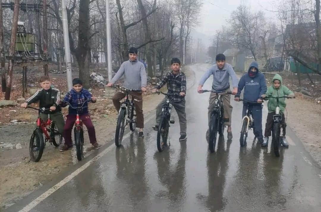 कुलगाम में बारिश के बीच साइकिल चलाते बच्चे। संवाद