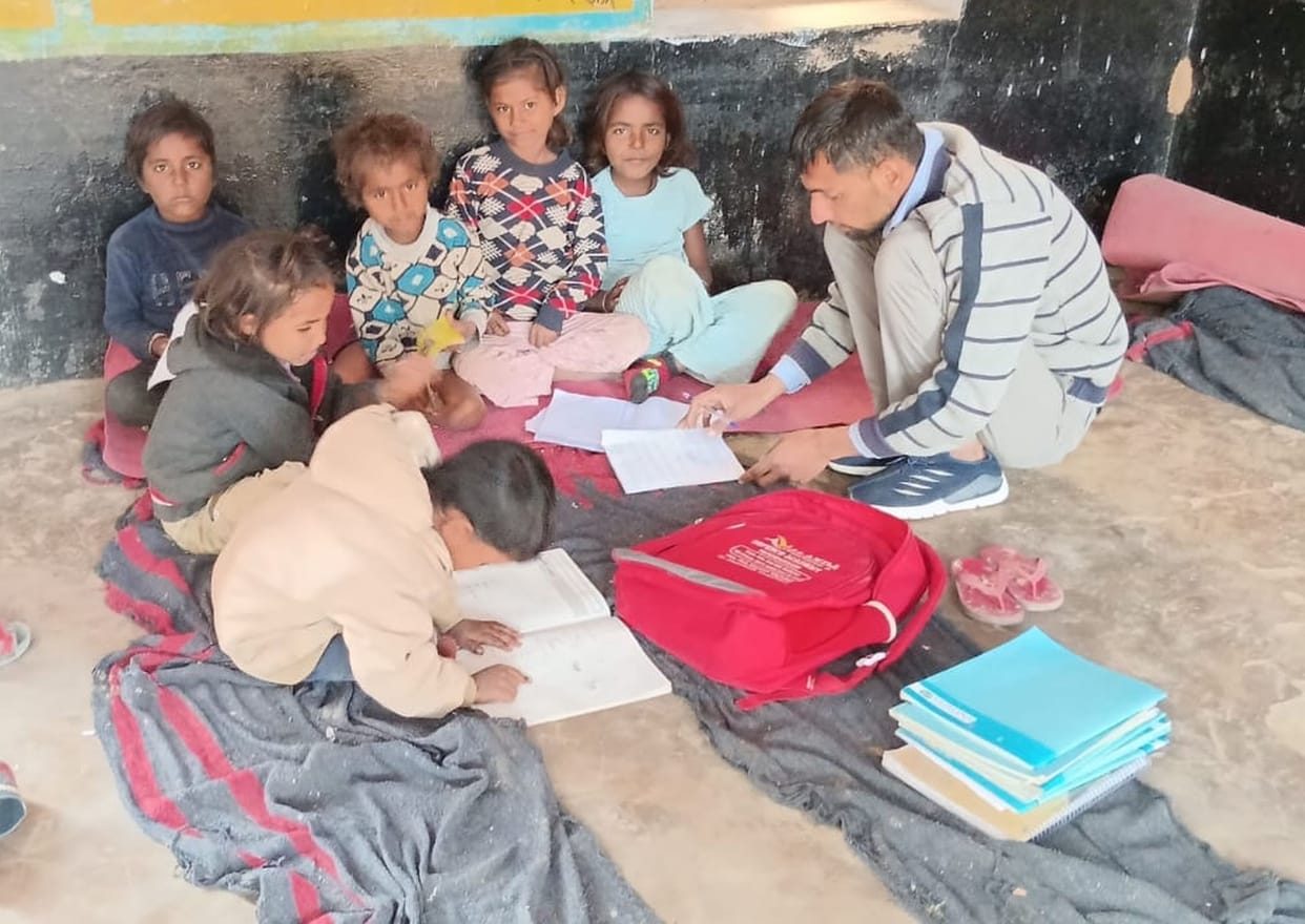 Innocent children studying while sitting on broken desks and torn mats.