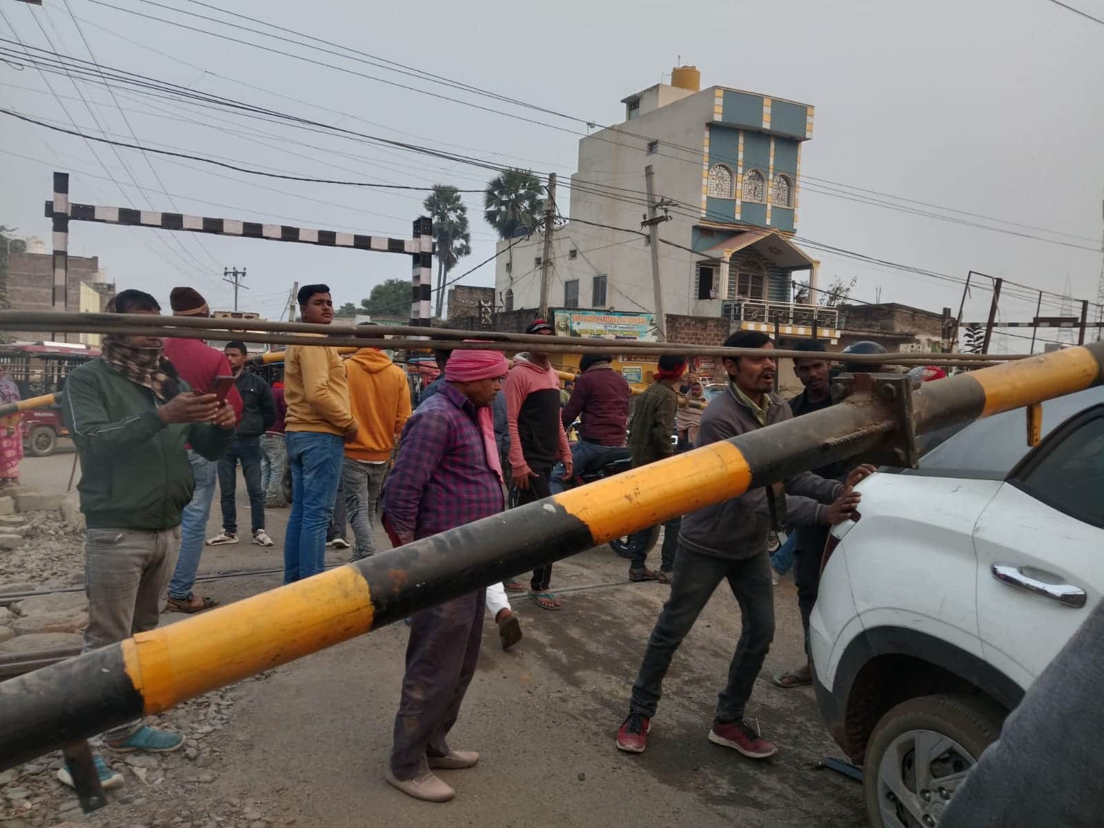 रेलवे फाटक में फंसी कार तथा घटनास्थल पर लोगों की भीड़