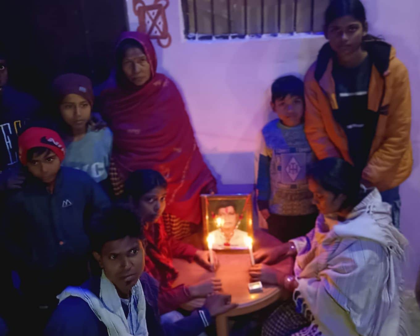 फोटो नंबर-35-दिवंगत विनोद के चित्र के सामने मोमबत्ती जलाकर श्रद्धांजलि देती पत्नी प्रीत्री, बहन