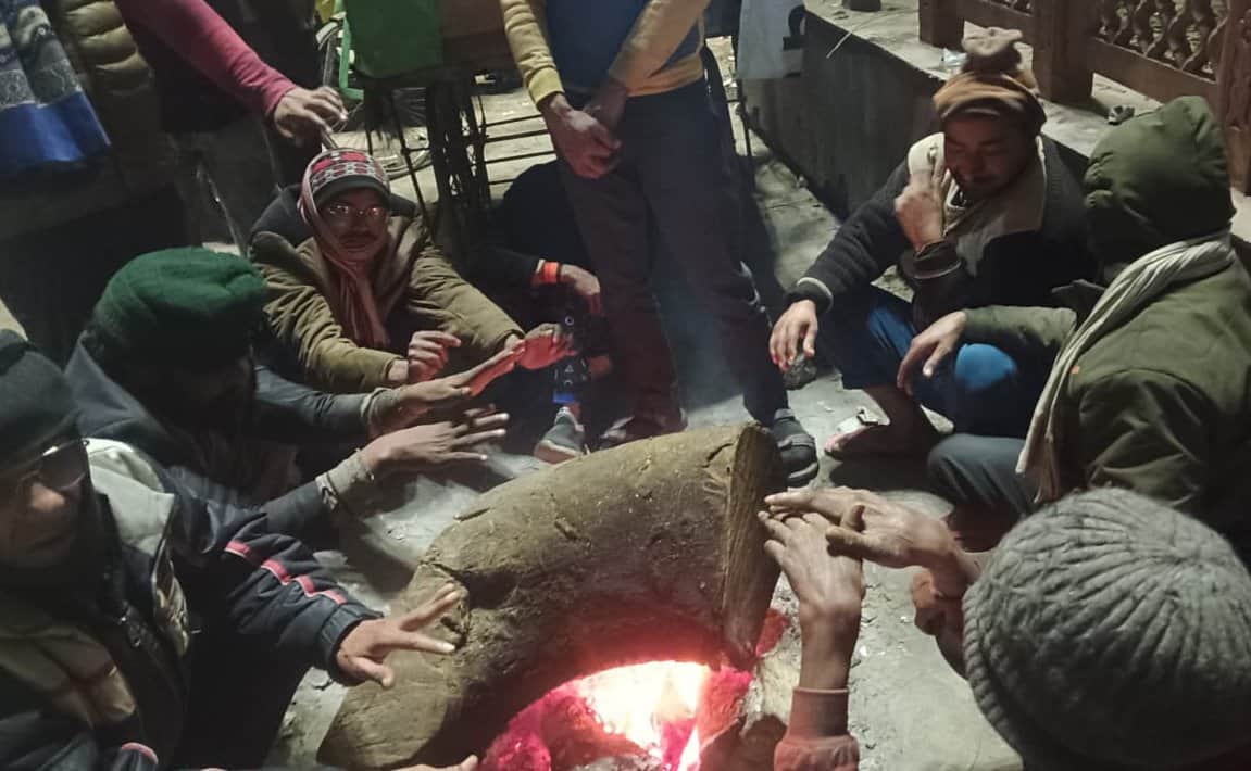 स्टेशन रोड तिराहे पर अलाव के समीप बैठे लोग। संवाद