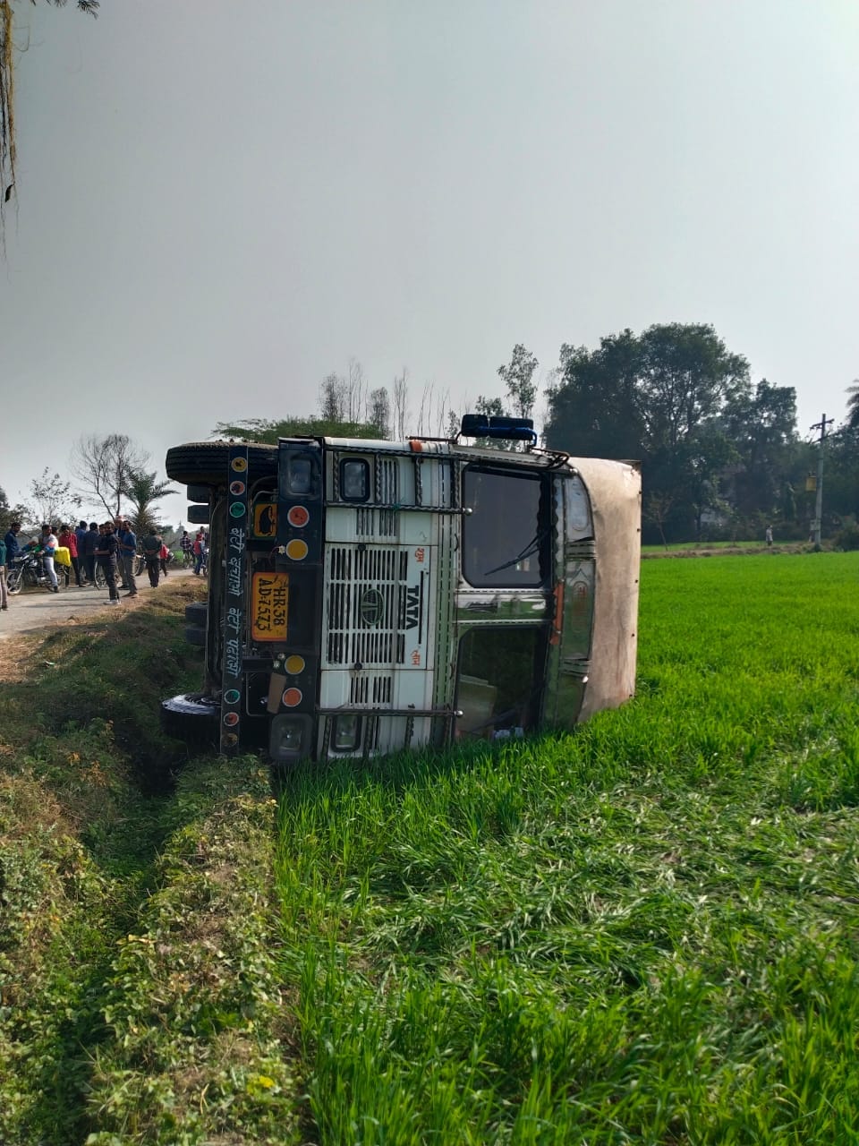 Truck overturns in field after hitting pole