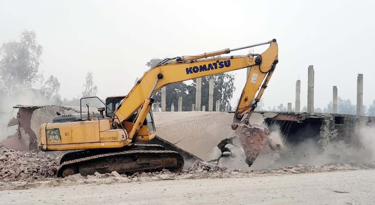 A JCB bulldozer demolished the building obstructing highway construction, and also flattened the crops.A JCB bulldozer demolished the building obstructing highway construction, and also flattened the crops.