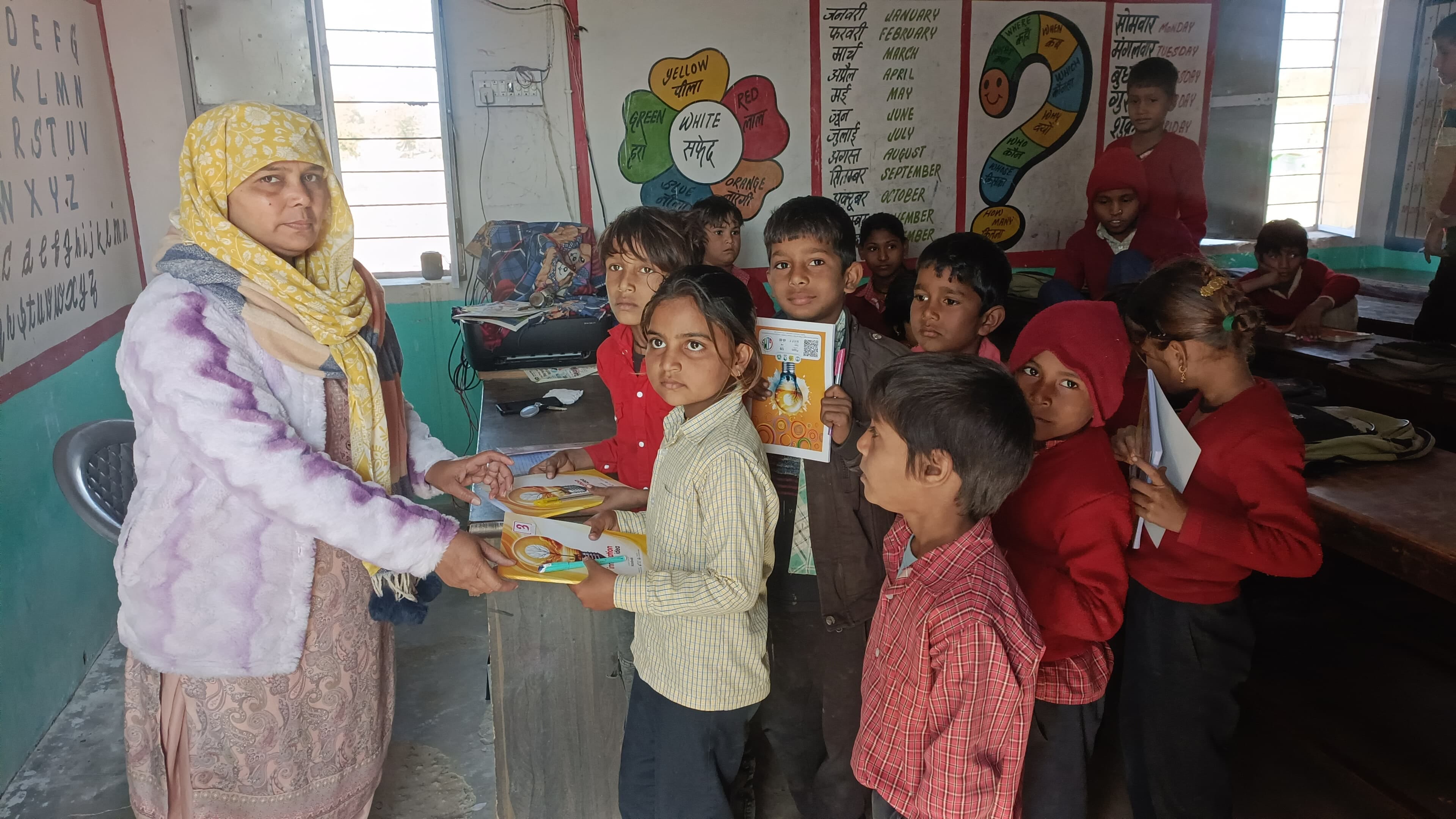 बच्चों को पाठ्य सामग्री वितरित करती हुई अध्यापिका।
