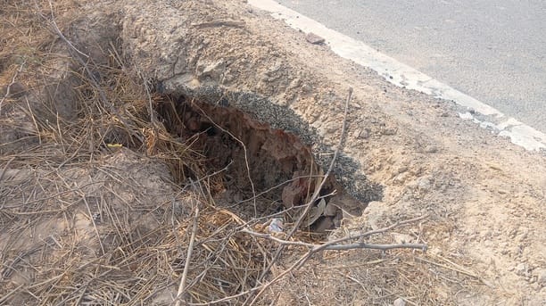 The soil beneath the road has slipped, causing a potential accident.