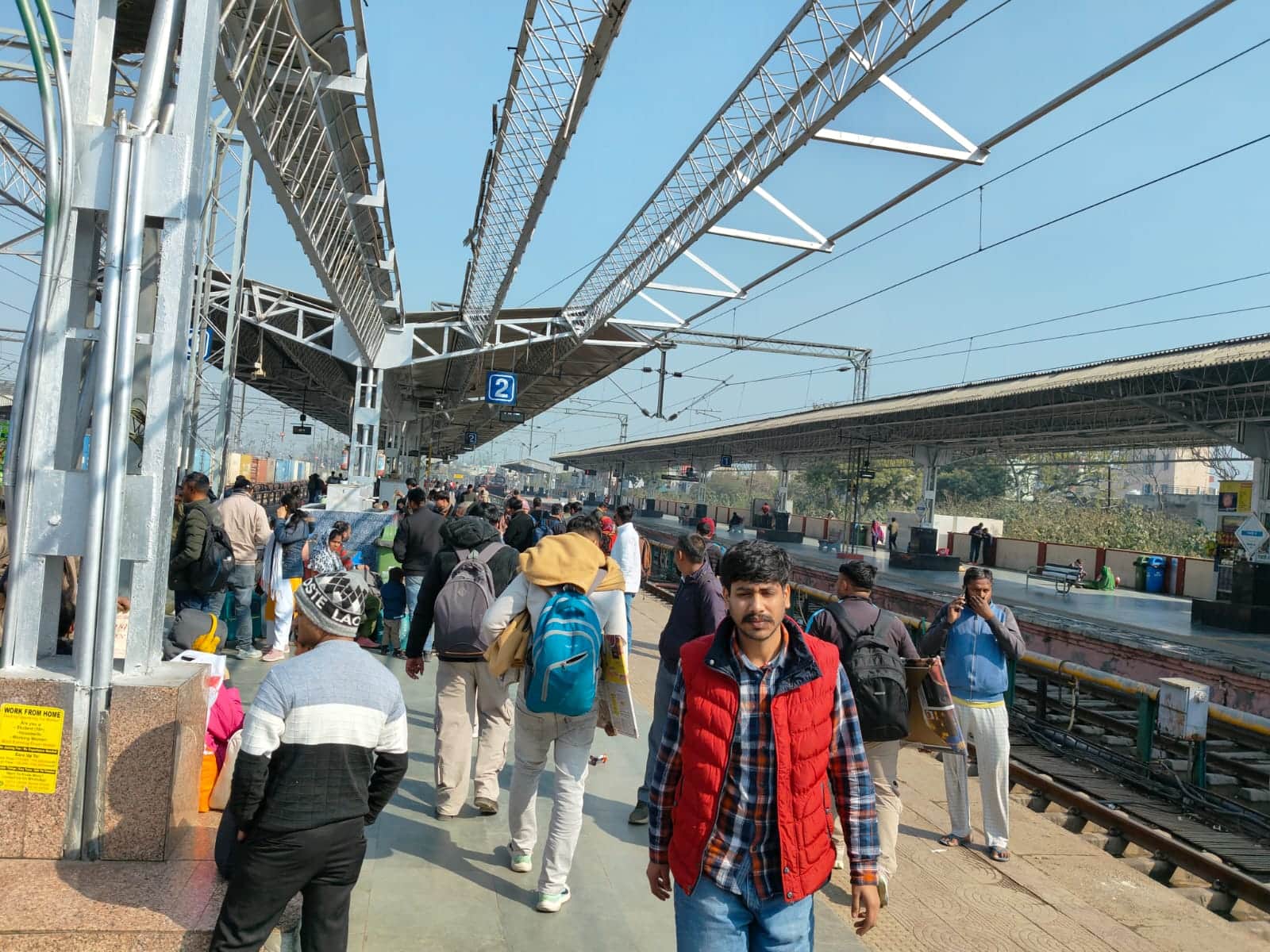 रेवाड़ी रेलवे स्टेशन पर ट्रेन पकड़ने के लिए खड़े लोग। संवाद