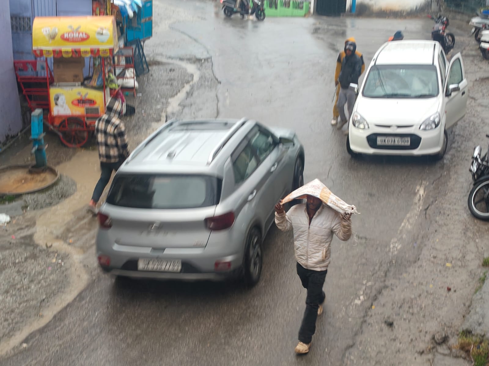  चंपावत नगर में बारिश के बाद प्लास्टिक का कट्टा सिर पर डाल कर जाता मजदूर। संवाद