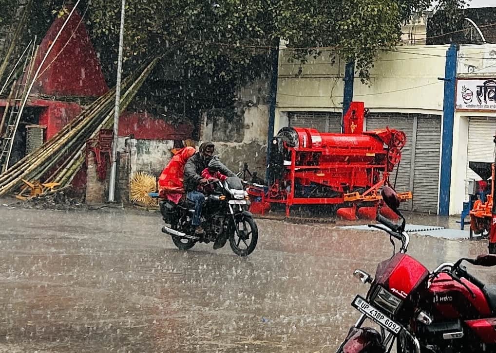 बारिश में भीगते हुए जाता बाइक सवार परिवार।