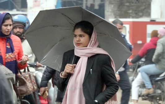 बिजनौर में बारिश में छाता लगाकर जाती युवती। संवाद