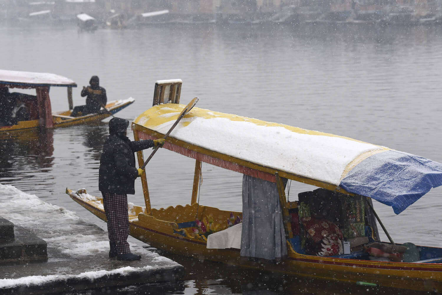 श्रीनगर में मंगलवार को हुई बर्फबारी के दौरान डल में शिकारे। बासित जरगर