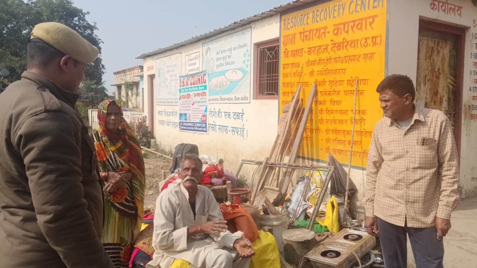 बरहज के कपरवार स्थित आरआरसी सेंटर के बाहर घरेलू सामान के साथ बैठे दंपत्ति से जानकारी लेते प्र