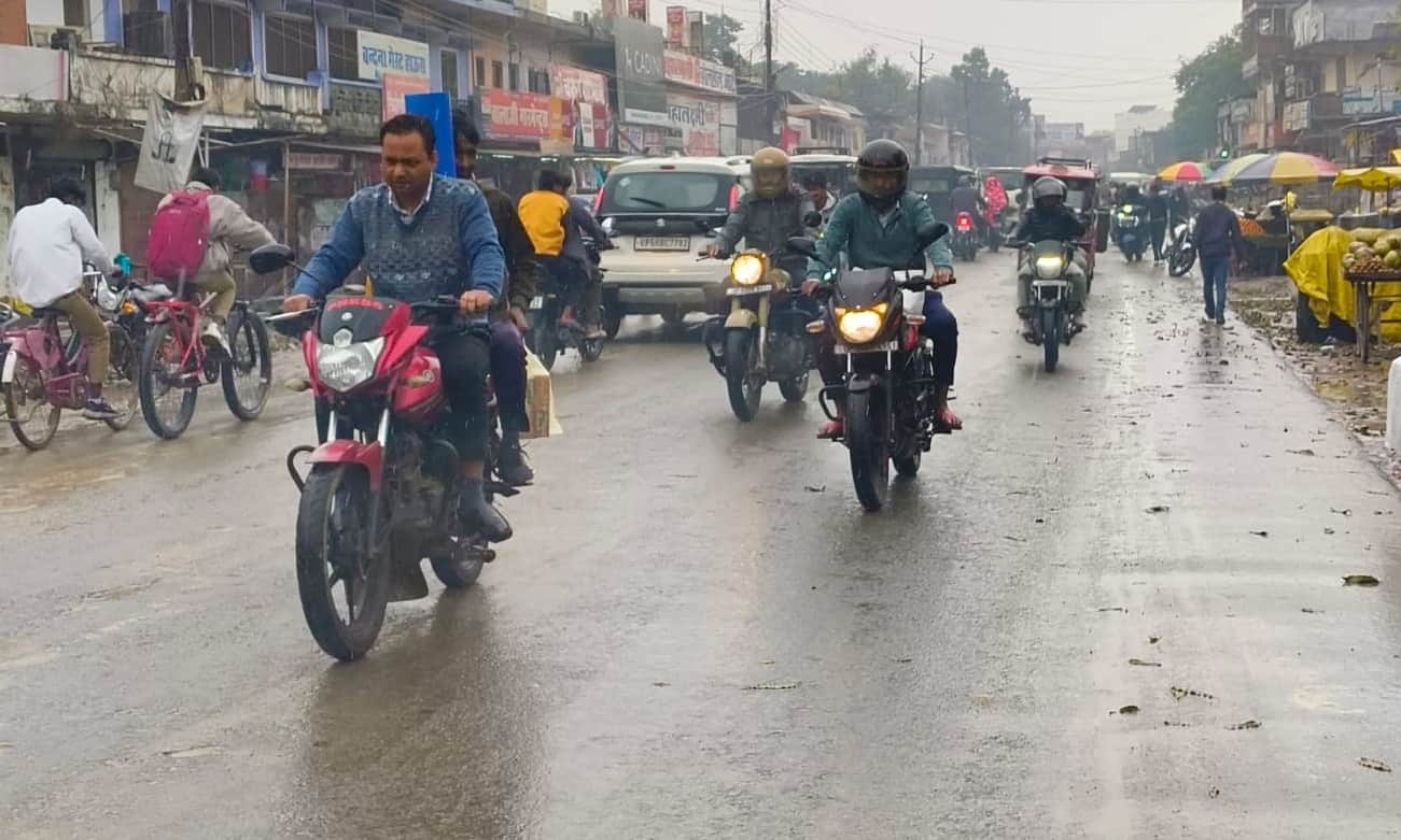 बस स्टेशन के पास बारिश के दौरान आते जाते लोग। 