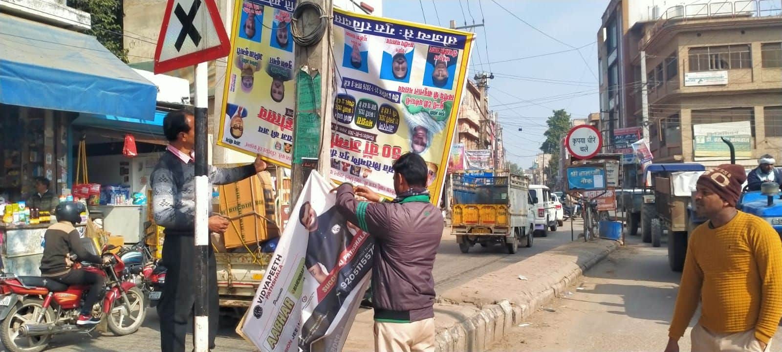 फोटो संख्या:66- बालाजी चौक पर पोल से होर्डिंग्स हटाते नपा  कर्मचारी---संवाद