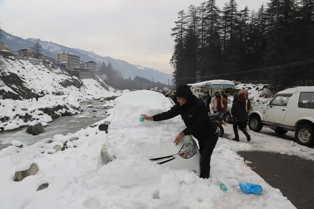 मनाली में वाहन से बर्फ हटाने में जुटा पर्यटक।-संवाद