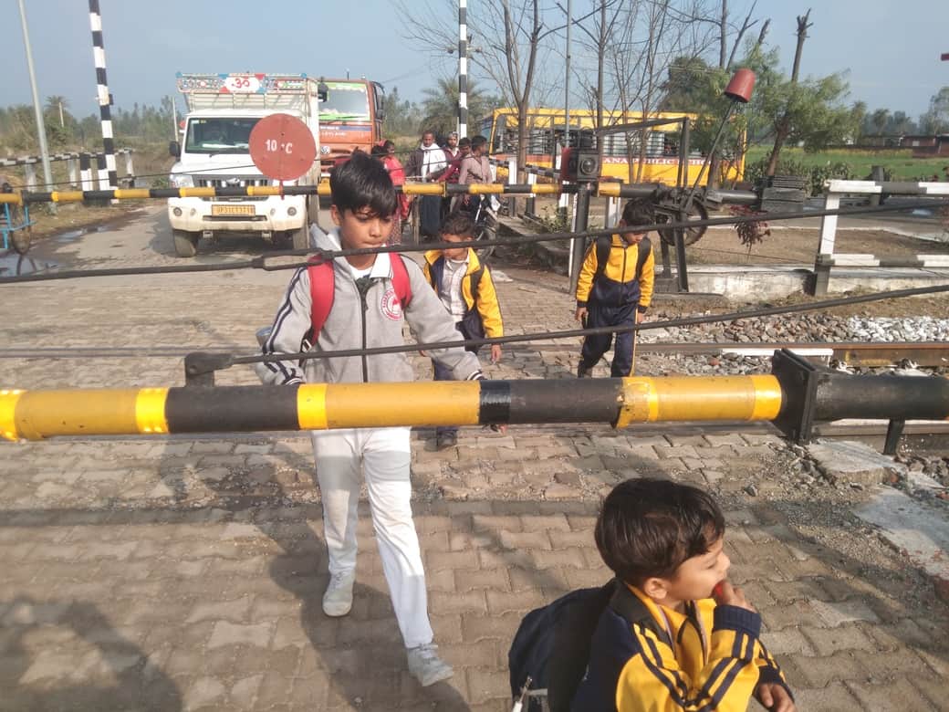 निगोही में बंद क्रॉसिंग से गुजरते बच्चे। संवाद