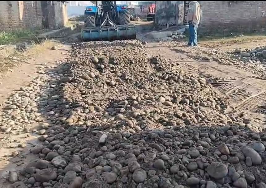 गुढ़ा मन्हांसा में मार्ग पर मिट्टी डालकर समतल करता ट्रैक्टर चालक।