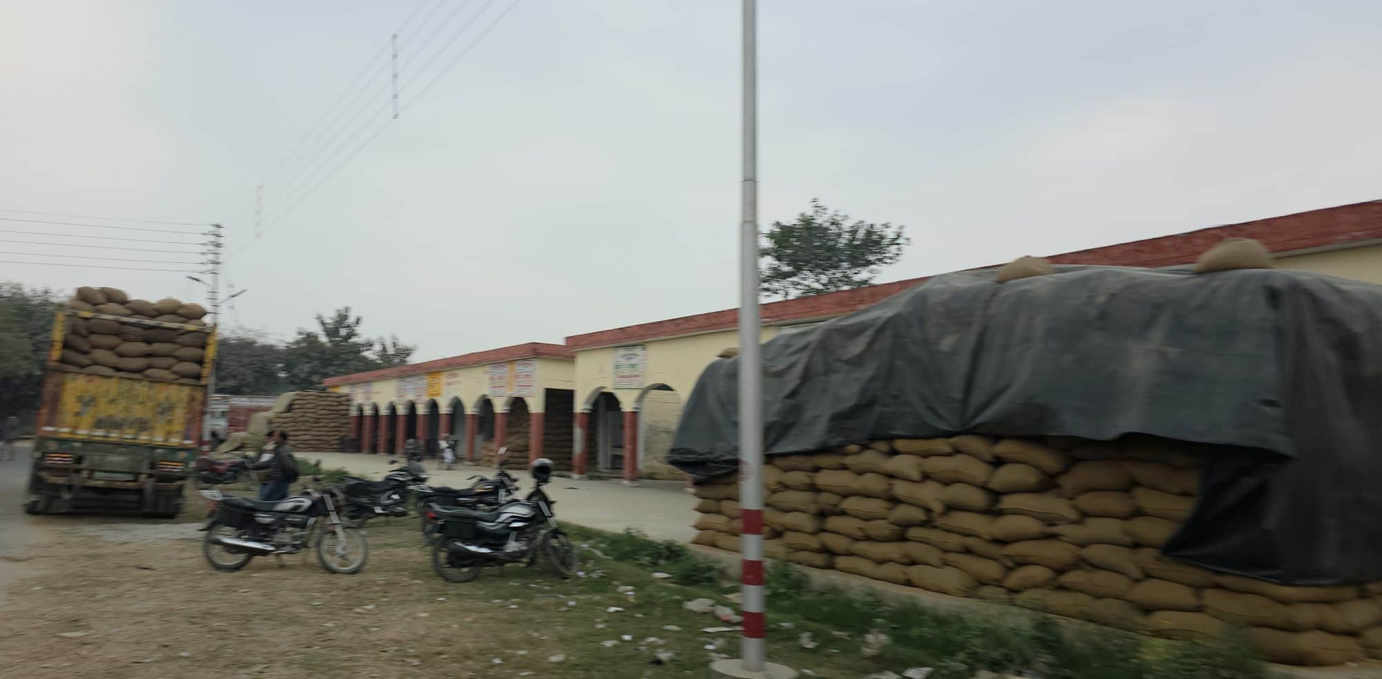 नवीन मंडी अकबरपुर परिसर में रखे धान के बोरे व खड़ा ट्रक। 