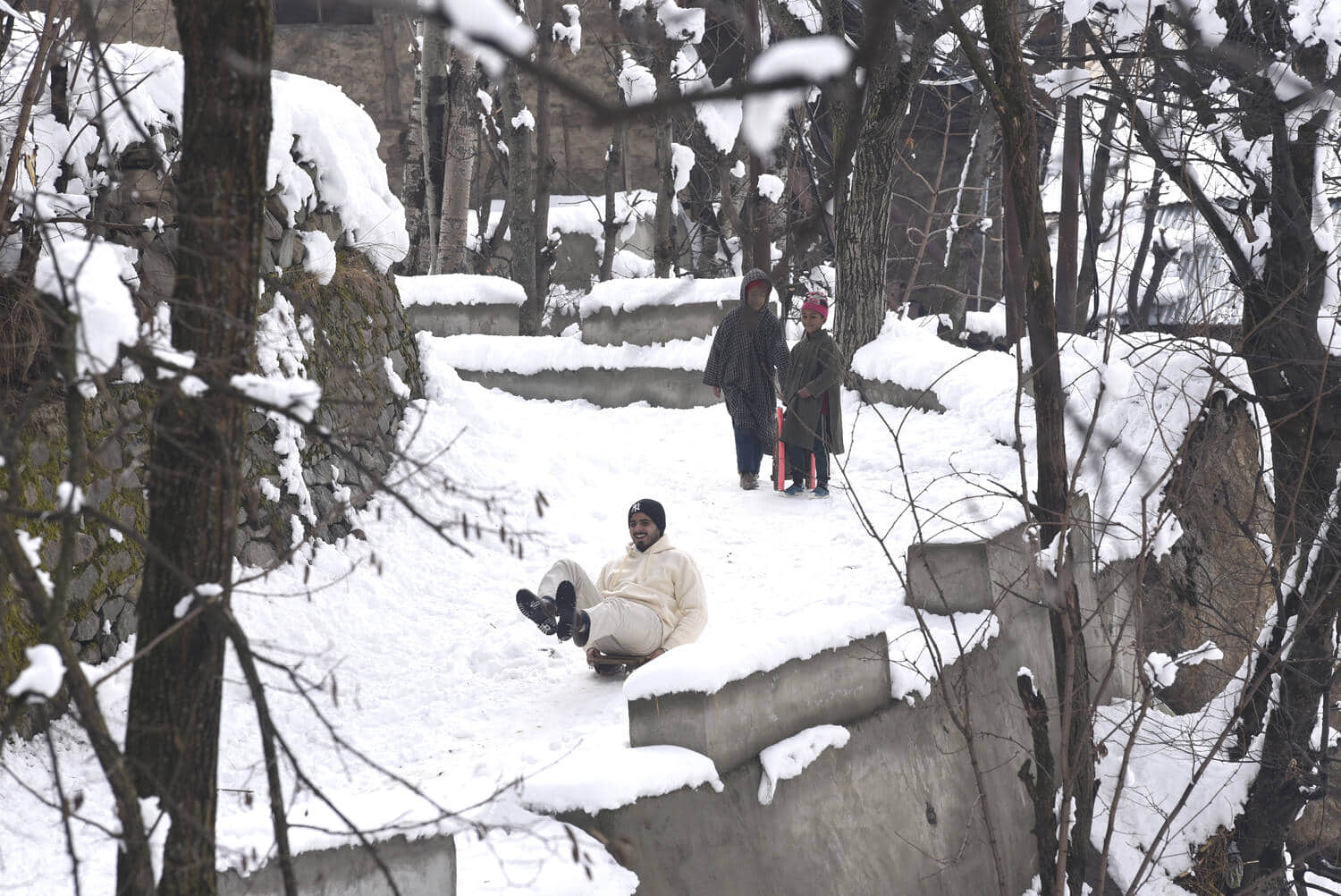 श्रीनगर के बाहरी इलाके फकीर गुजरी में जमी बर्फ में फिसलते बच्चे। बासित जरगर