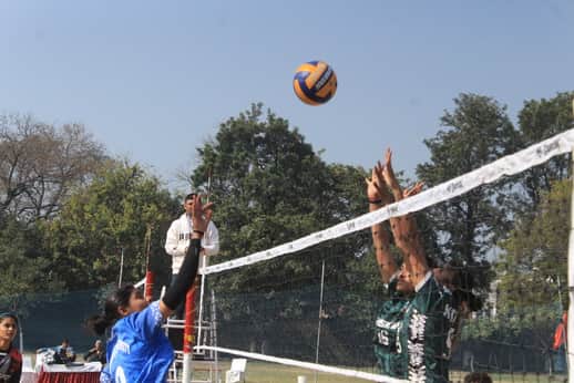 वालीबॉल प्रतियोगिता में बॉल को स्मैश मारने का प्रयास करती महिला खिलाड़ी। संवाद