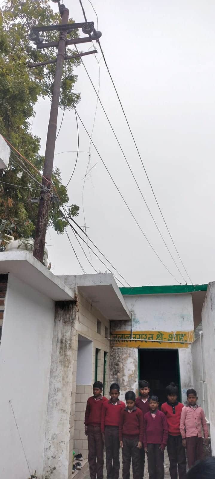 प्राथमिक विद्यालय तारीन जलालनगर के अंदर लगा बिजली का खंभा और खड़े बच्चे। संवाद