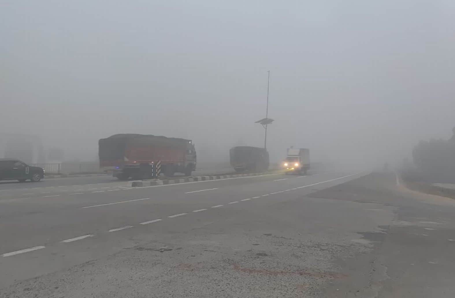  कोहरे के बीच गुजरते वाहन। 