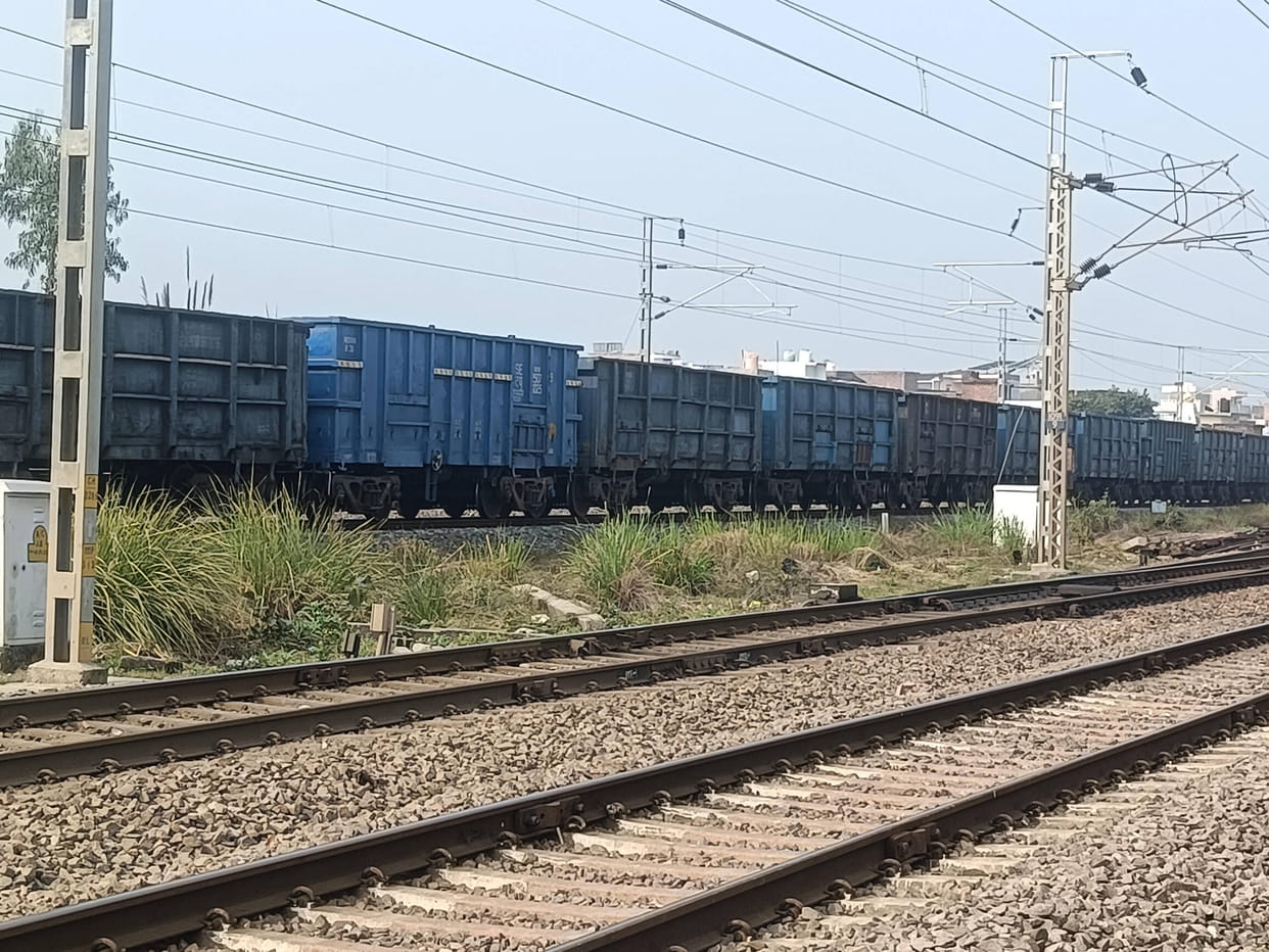 A freight train parked at the level crossing, causing a traffic jam