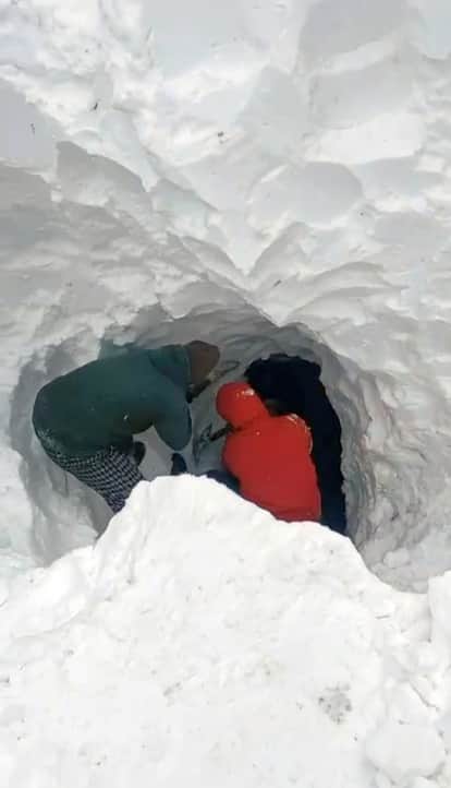 Workers are courageously making a path for water through the snow.