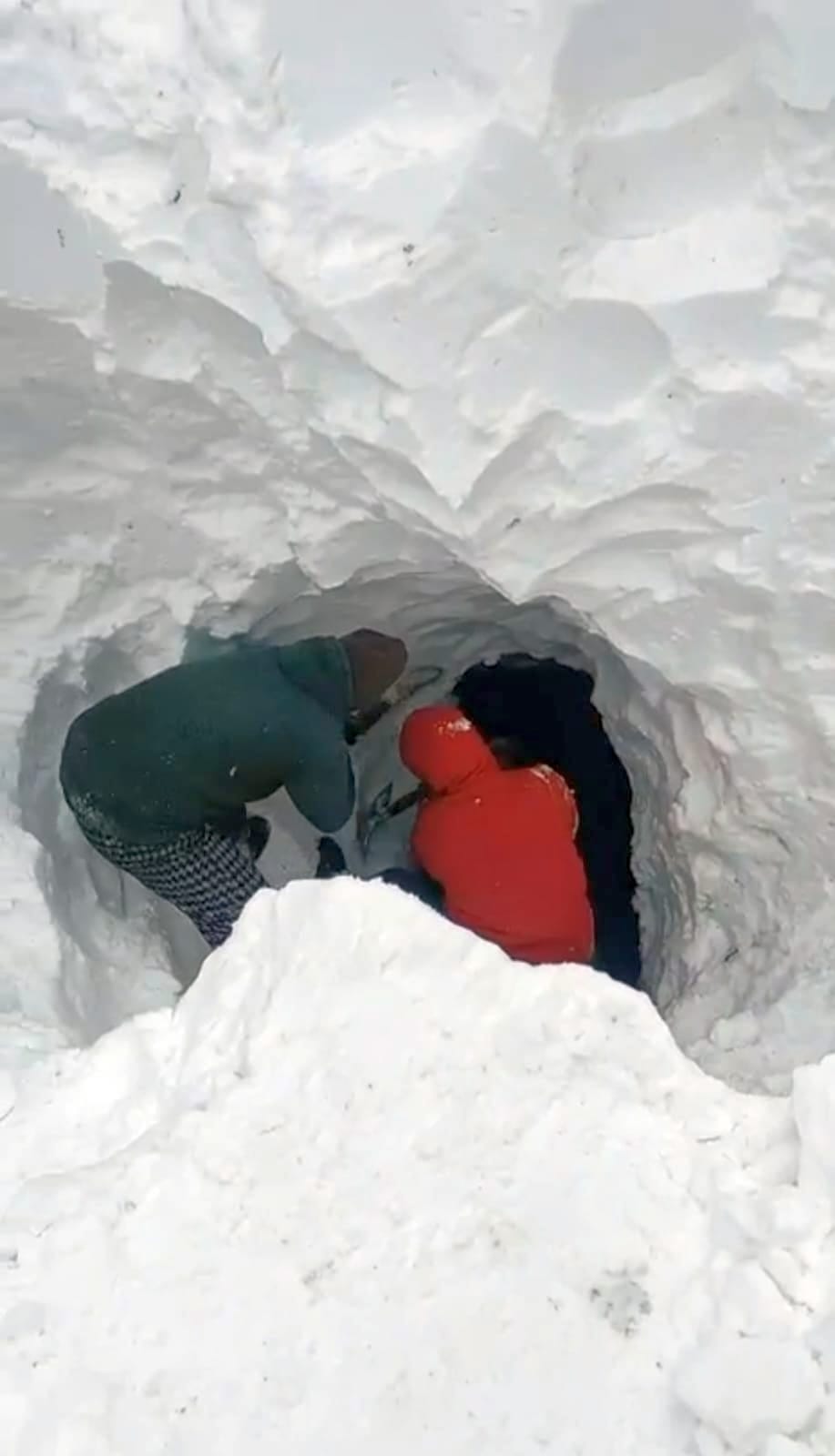 Workers are courageously making a path for water through the snow.
