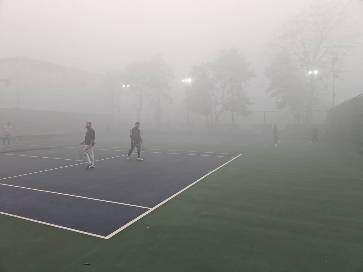 Tennis players practicing amidst the fog