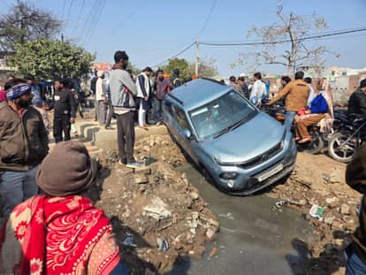 Car hanging from the bridge of a drain under construction