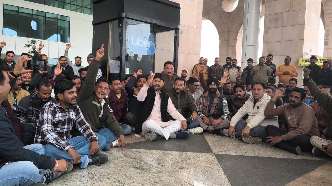उबर कंपनी के काउंटर के सामने बैठकर प्रदर्शन करते टैक्सी चालक और कांग्रेस जिलाध्यक्ष: संवाद