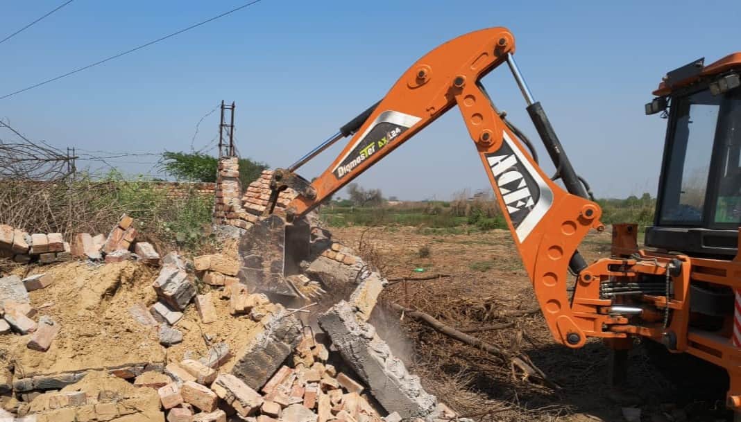 अवैध निर्माण को तोड़ती जेसीबी। 
