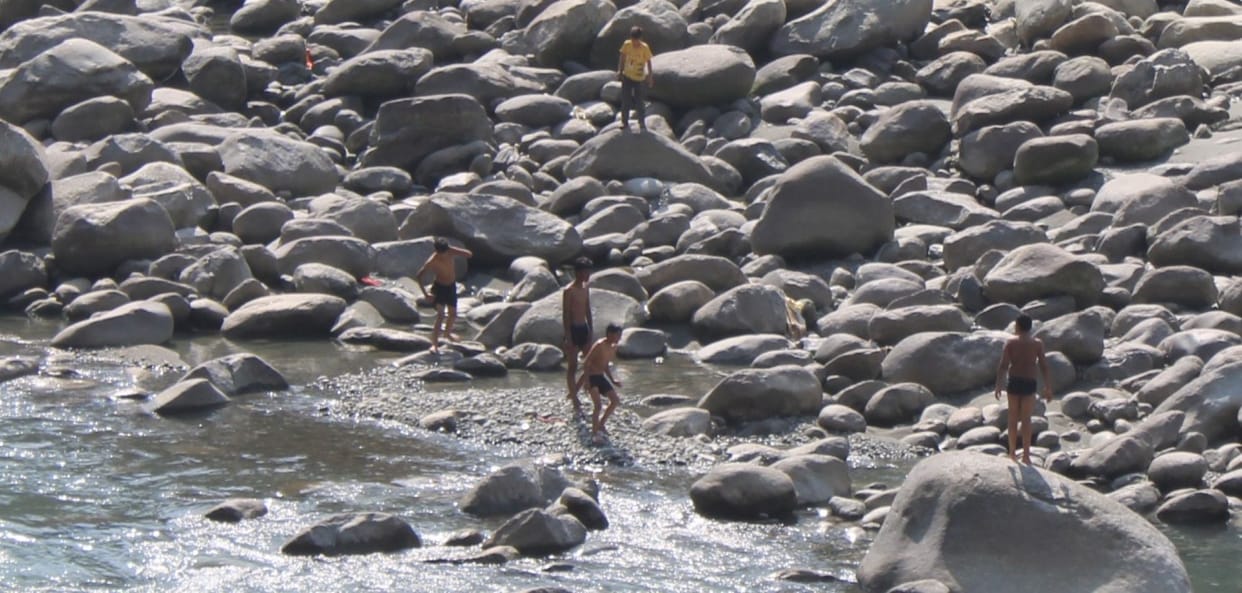 Groups of young men take a risky dip in the strong current of the Ravi River.