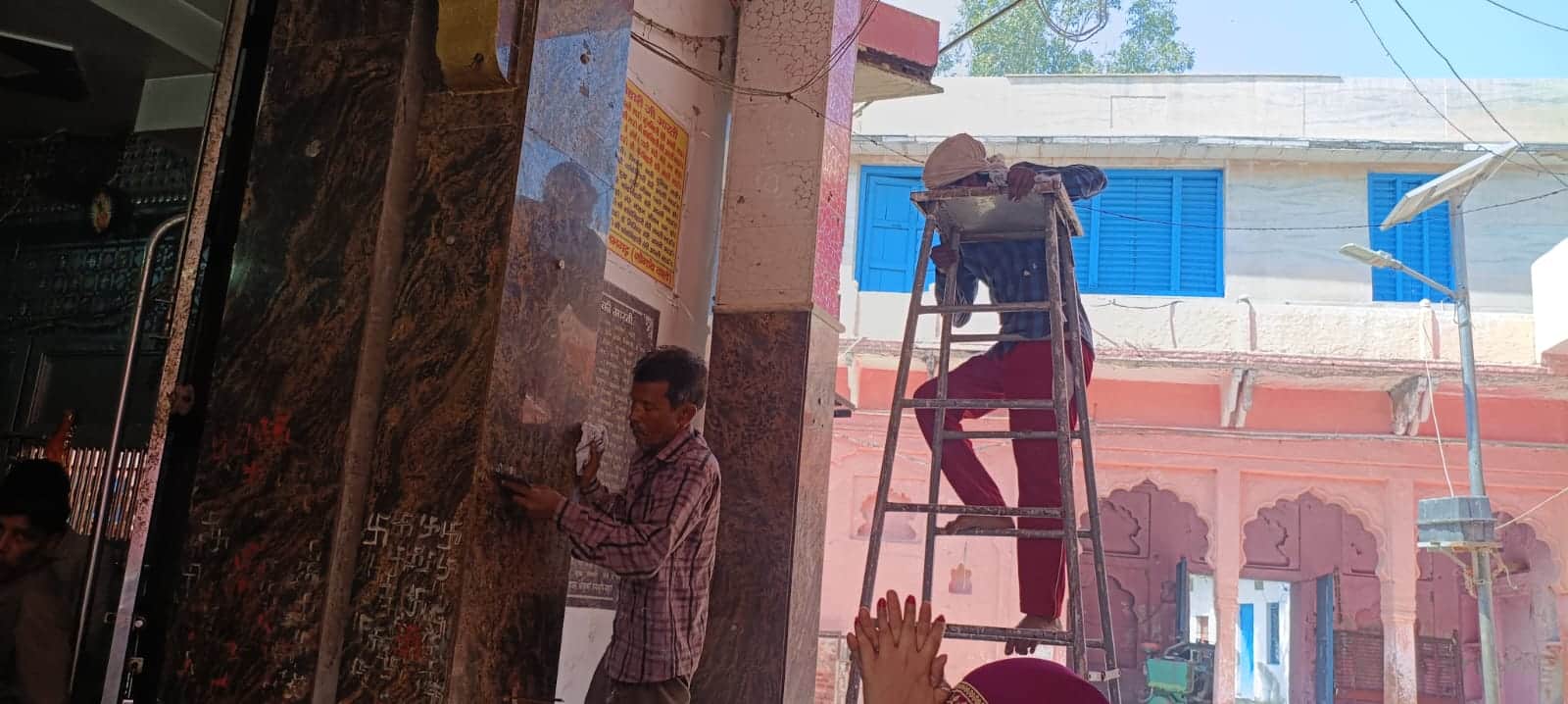 गांव सेमरी स्थित नरी सेमरी मंदिर में दीवार पर लगी गंदगी को हटाते मजदूर।
