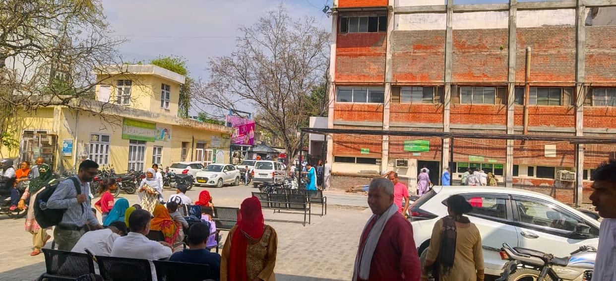 Patients stand in the sun to get their test reports.