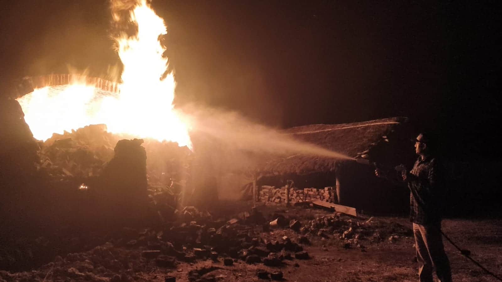 अवैध भट्टी में लगी आग को बुझाते दमकल कर्मी।