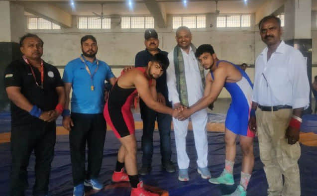  पहलवानों के हाथ मिलवाते अतिथि।