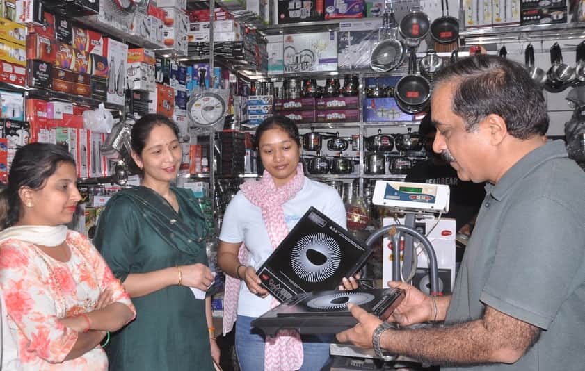 10-रोहतक स्थित गांधी कैंप की मार्केट में दुकान पर इंडक्शन चूल्हा खरीदतीं महिलाएं। संवाद