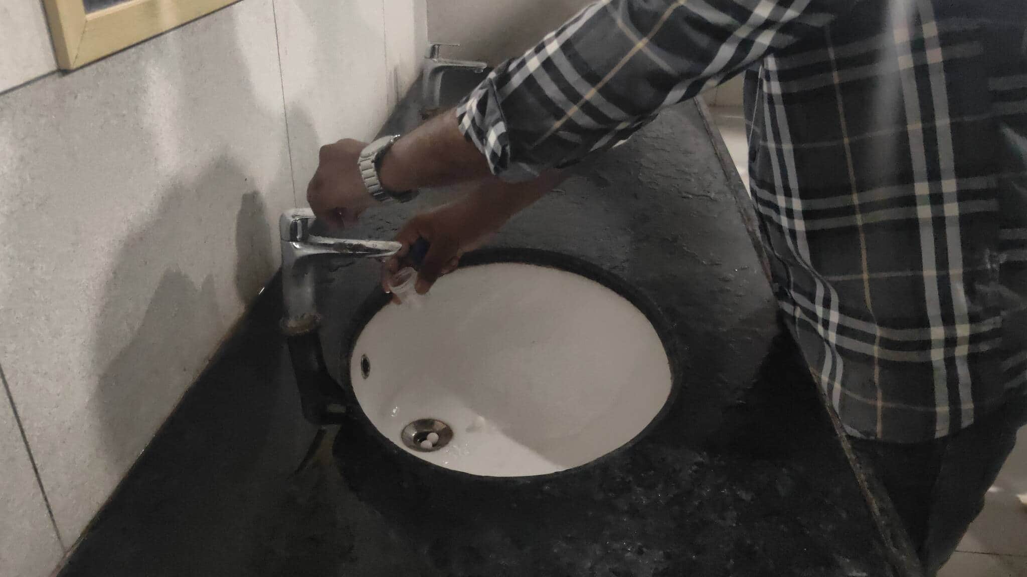 मेडिकल कॉलेज के शौचालय में पेशाब सैंपल के बाद खाली बोतल को पानी से साफ करता मरीज।