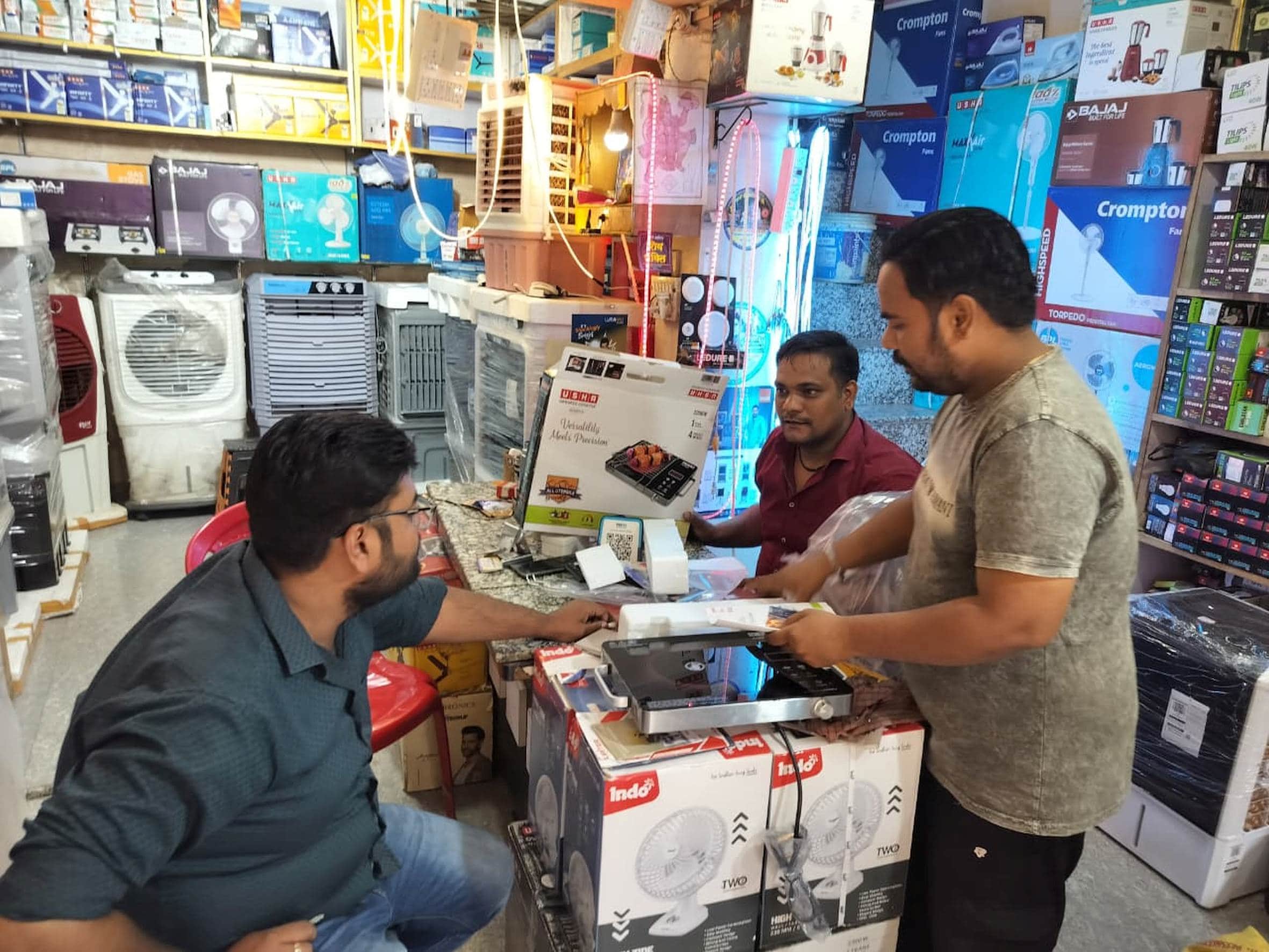 दुकानों पर इंडेक्शन चूल्हे की खरीदारी करते लोग।