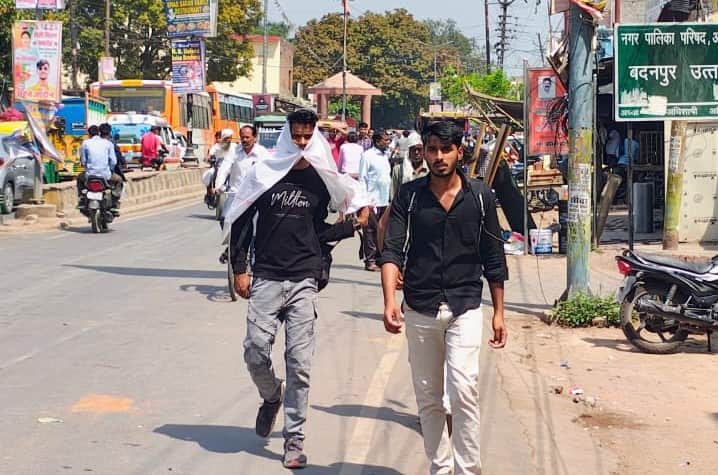 फोटो-29- धूप से बचने के लिए गमछा ओढ़कर जाते युवक। संवाद