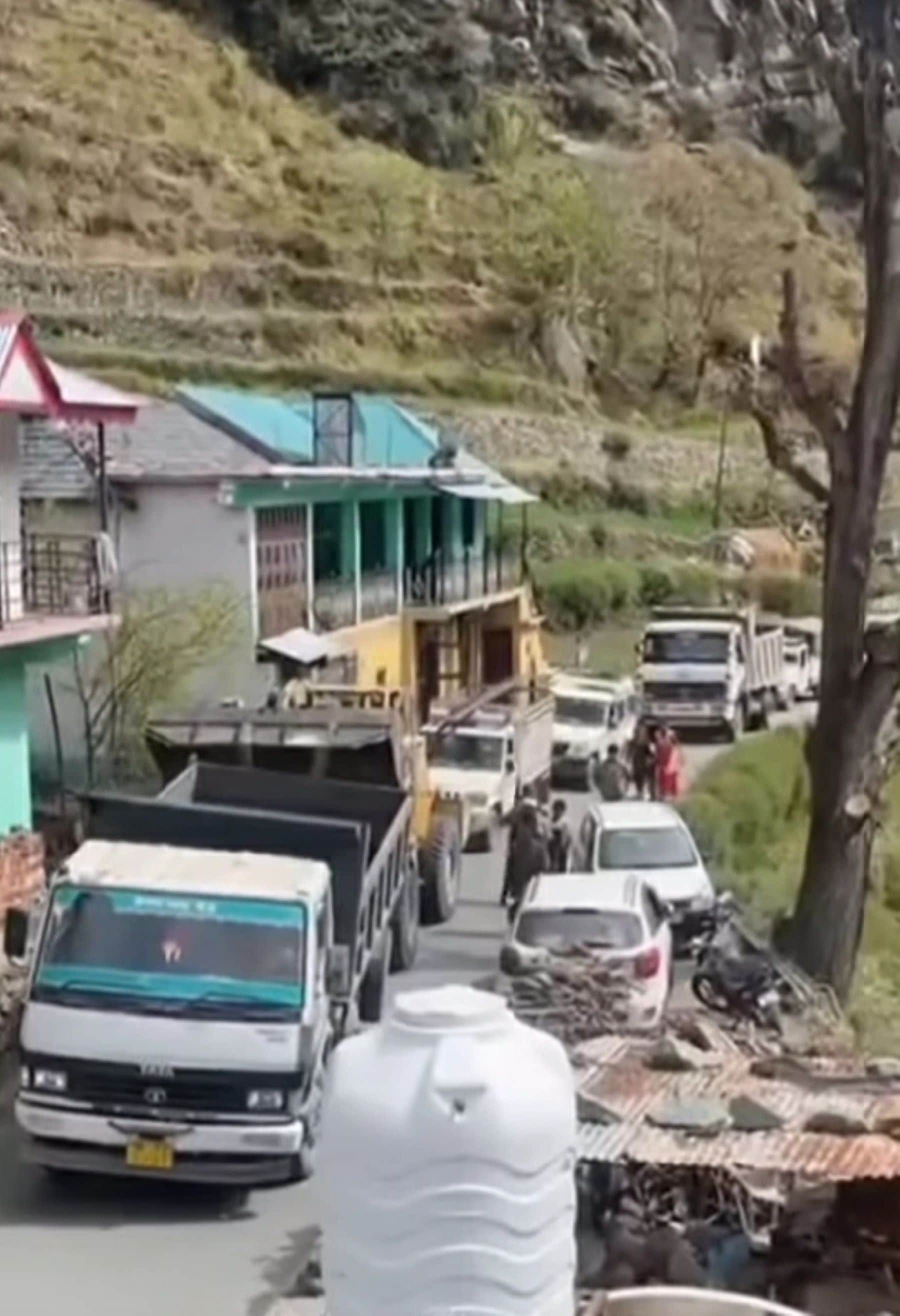 नकरोड़-चांजू सड़क पर खराबटिप्पर को हटाती जेसीबी मशीन, पीछे लगी वाहनों की लंबी कतारे।