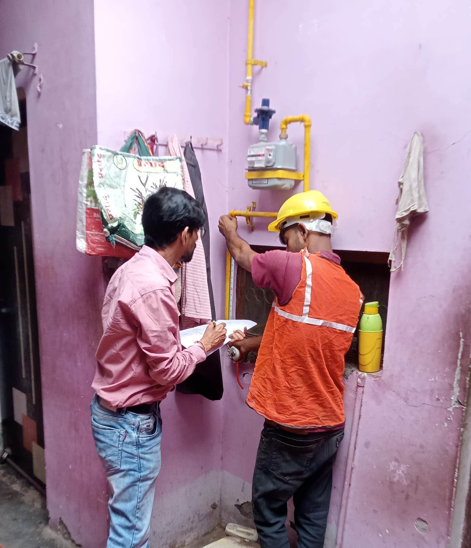 घर के अंदर पीएनजी कनेक्शन लगाते कर्मचारी।